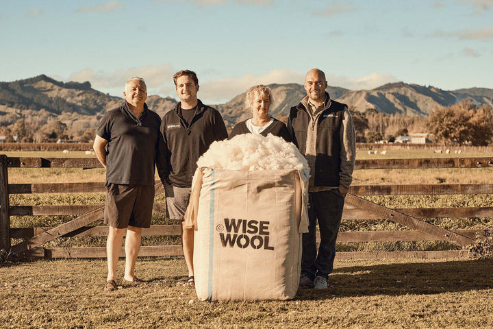 Four Wise Wool Employees on a Farm With a Big Bag of Wise Wool in Front of Them